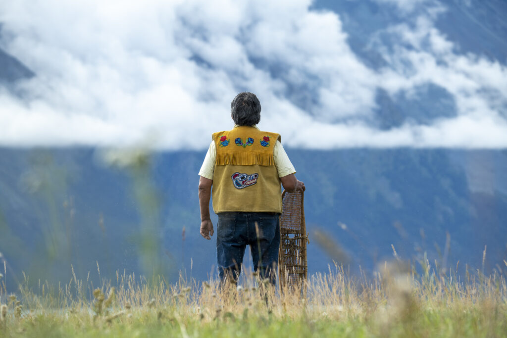 Man in beaded vest back turned